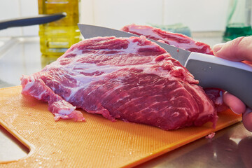 The knife cuts a large piece of meat with a layer of fat.