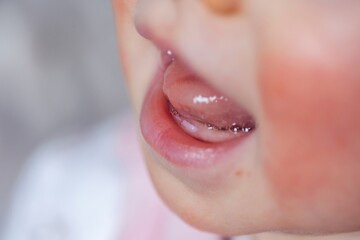 A close up portrait of a baby mouth with the first two small white teeth coming out of the gums...