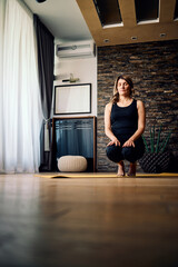 Fototapeta na wymiar Calm middle-aged woman practicing yoga at home.