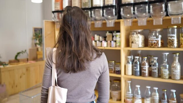 Woman in a mindful consumption store without packaging with pasta, nuts or grains in a store without plastic waste. Low-waste lifestyle. Sustainable ecological lifestyle