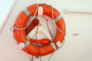 An old orange lifebuoy attached to the railing of a ship or ferry.