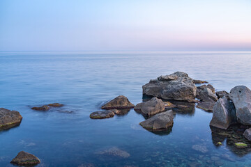 Twilght over the wild rocky beach coastline and the sea. Sea and rocks at night wide angle view.
