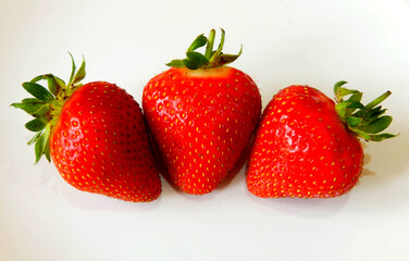 Three strawberries isolated against a plain white background. No people.