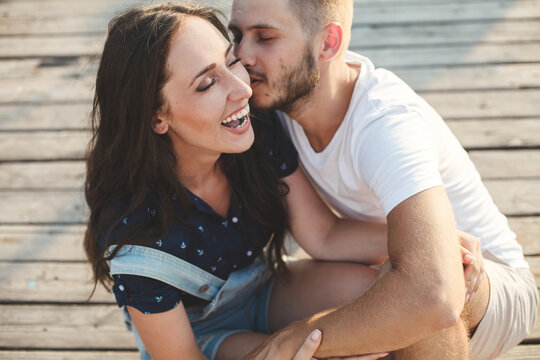 Lovers, guy and girl, close-up laughing against the backdrop of a wooden pier.