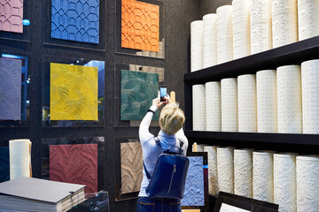 Woman choose wallpaper samples in store