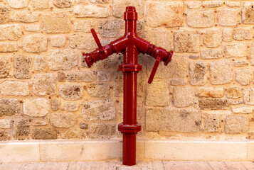 Painted ref fire hydrant in old town street. Red color on stone wall background. Fire safety concept
