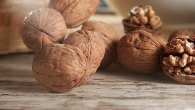 Walnuts falling on a wooden table in slow motion