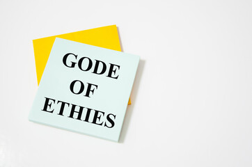 Code of ethics text written on a white notepad with colored pencils and a yellow background