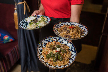 The waiter serves pilaf with dolma and khinkale