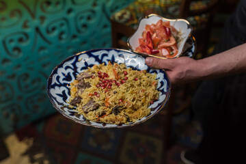 The waiter serves pilaf with pomegranate and tomatoes