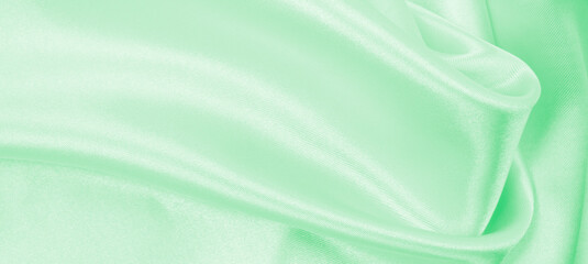 Smooth elegant green silk or satin luxury cloth texture as abstract background. Luxurious background design
