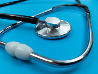 Black stethoscope on blue background. Stock photo.