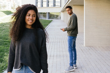 Afro man walking and looking in awe at another seductive girl. Boy looks attentively at an afro girl walking down the street.