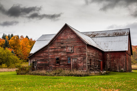 rustic barn house in the countryside with autumn foliage  at the background.