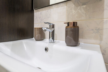 metal water tap sink with faucet with soap and shampoo dispensers in expensive bathroom