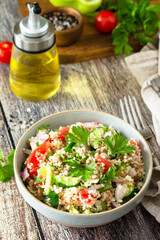 Food dieting concept, tuna salad. Couscous salad with conserved tuna, tomatoes, cucumbers and purple onions on rustic wooden table.