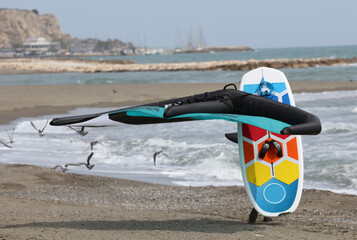 rider walks with foilboard comet, board and hydrofoil, on the beach