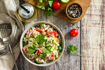 Food dieting concept, tuna salad. Couscous salad with conserved tuna, tomatoes, cucumbers and purple onions on rustic wooden table. Top view flat lay.