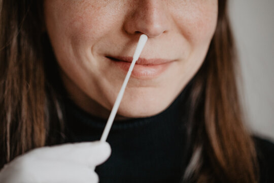 Frau macht Corona Schnelltest mittels Abstrich in Nase mit Teststäbchen zu Hause