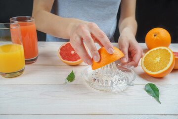 Young woman squeezes orange juice using a manual glass juicer