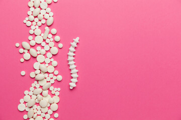Spine treatment. Organ model lying on a pink background with pills. Copy space for text.