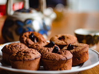 Several buckwheat gluten free cupcakes with dates on a plate and table, teapot and cup on background