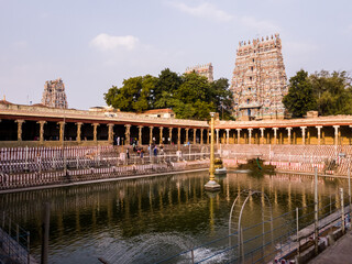 The temple tank surrounded by the tower spires of the ancient Hindu temple complex of Meenakashi Amman in the city of Madurai.