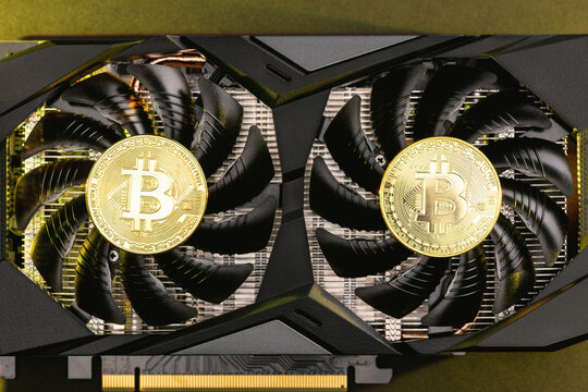 Two gold bitcoin on a  video Card with gold backlight. Crypto currency, top view. Bitcoin mining concept