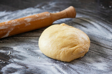 Fresh dough ready to bake. Bread dough on wooden kitchen counter with rolling pin