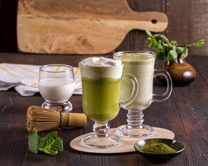 Matcha green latte tea ,matcha powder and bamboo whisk on wood background.