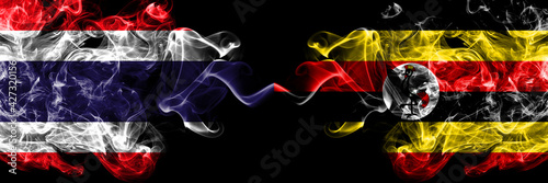 Thailand, Thai vs Uganda smoky mystic flags placed side by side. Thick colored silky abstract smokes flags.