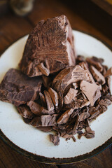 large and small pieces of chocolate. crushed chocolate on a white plate. dark chocolate top view. chocolate macro photo