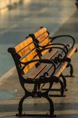 A couple of classic benches in a street, isolated, washed under morning sun.