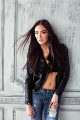 young brunette woman in leather jacket at vintage wall