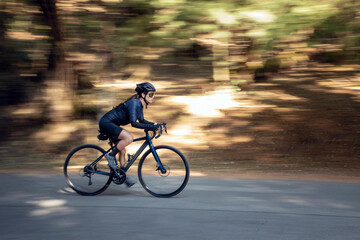Fototapeta na wymiar Mujer en bicicleta de pista en una carretera en medio del bosque. concepto de deporte al aire libre. 