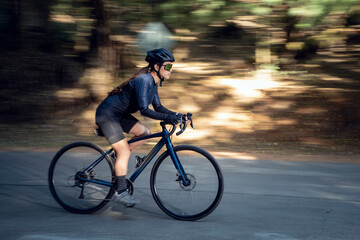 Mujer latina montando en bicicleta en una carretera en medio del bosque. Concepto deporte al aire libre