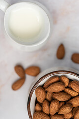 Vegan almond milk in jug and almond on white marble background. Non dairy alternative milk.Top view.