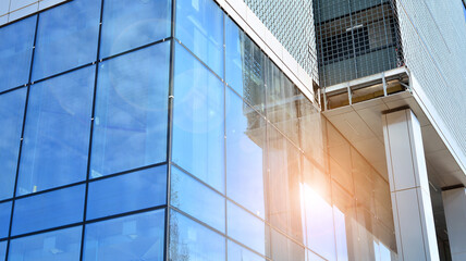 Obraz premium Glass clad facade of a modern building covered in reflective plate glass.