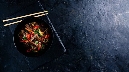 Obraz na płótnie Canvas Stir fry soba noodles with beef and vegetables in wok on dark background, Asian noodles with beef WOK in black bowl