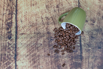 Coffee beans in a green mug on a wooden background