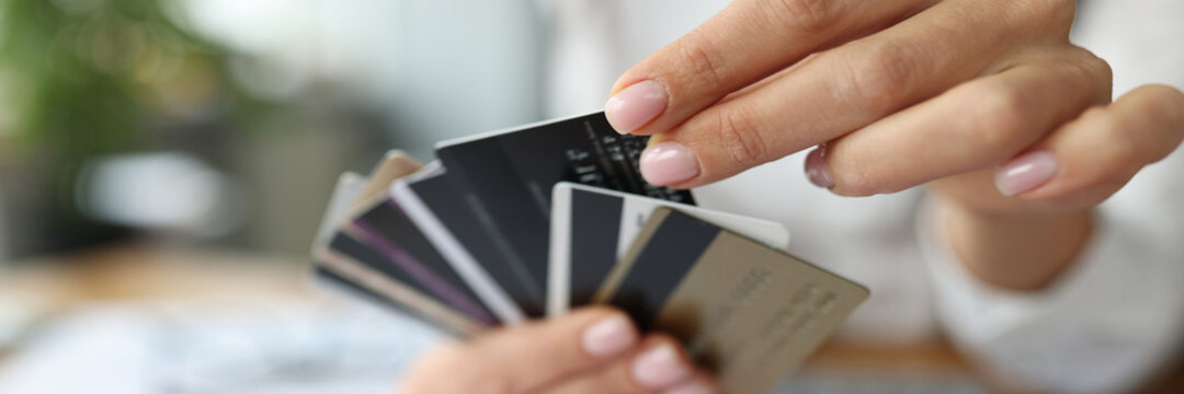 Fan of plastic credit cards is in woman's hand.