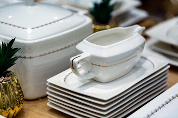 Sauce boat, Empty square plates and ceramic white pot with lid on wooden table. holiday interior decor. Set elegant porcelain dishes. Selective focus, shot with shallow depth of field. Table setting.