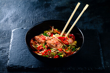 Asia food. Udon noodles with salmon and shrimp on black table.