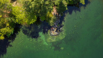 Top aerial view of two Adirondack chairs on a rock formation facing a lake in Muskoka, Ontario Canada during a summer sunny morning.