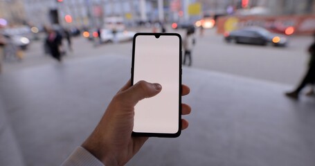 Male hand holding smartphone mockup in a city tap on a touchscreen empty screen chromakey