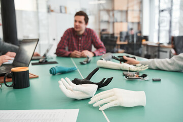 People studying structure of prototype of mechanical plastic hand