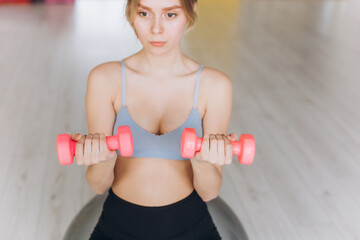 Girl doing exercise with dumbbells in the gym. Sport, healthy lifestyle concept