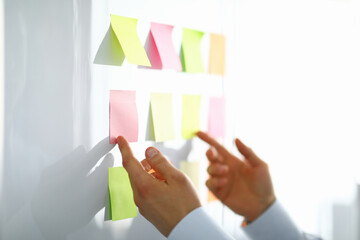 Close-up of worker hand holding colorful papers for notes with information