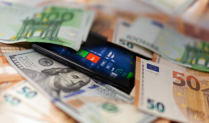 Mobile banking and finance concept: smartphone with stock exchange market application, euro and US dollar banknotes
