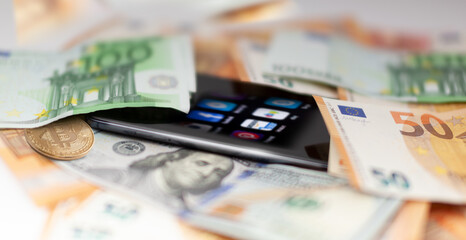 Mobile banking and finance concept: smartphone with applications, euro, US dollar banknotes, and bitcoin.